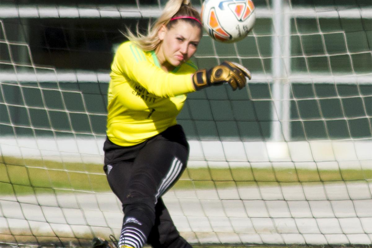 A female soccer player kicks a ball